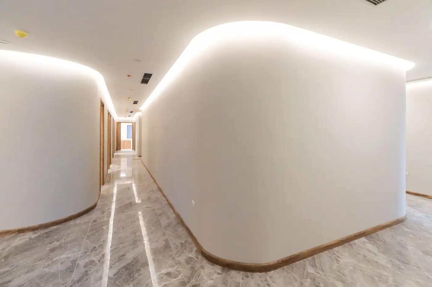 Bright modern hallway with curved walls and soft lighting, showcasing minimalist interior design.