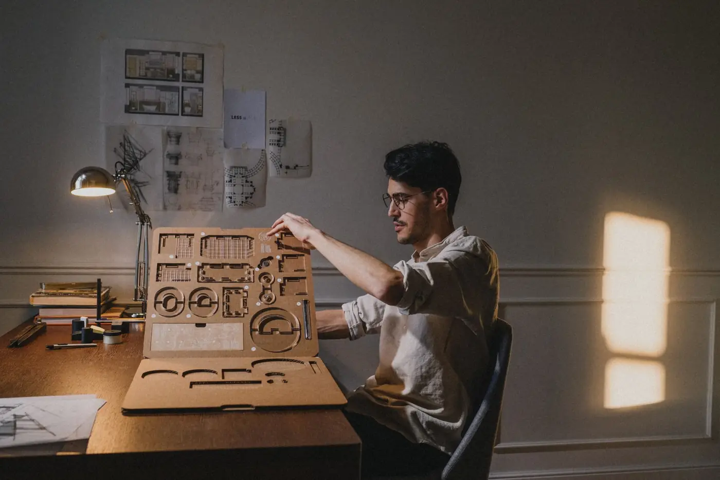 A focused architect working on a design at home with ambient daylight.